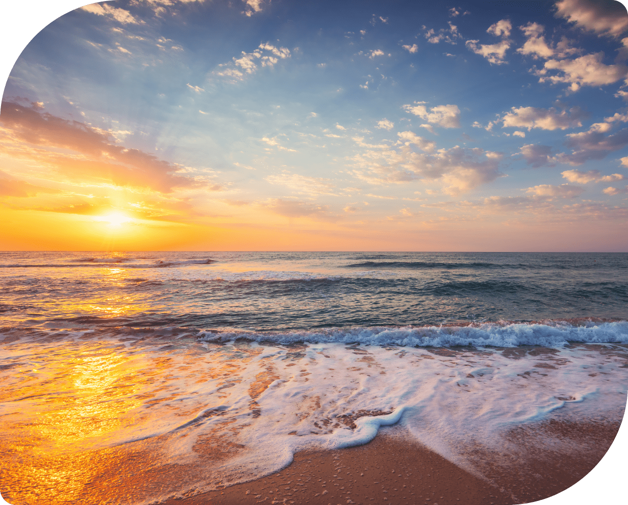 Sunset over a calm ocean with waves gently washing onto the shore.
