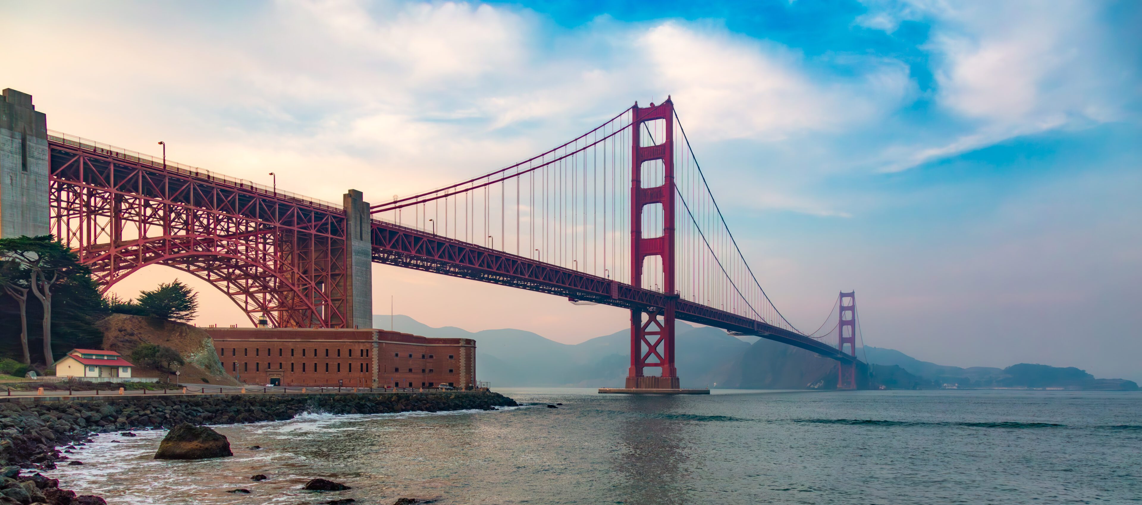 Golden Gate Bridge over water under a cloudy sky.
