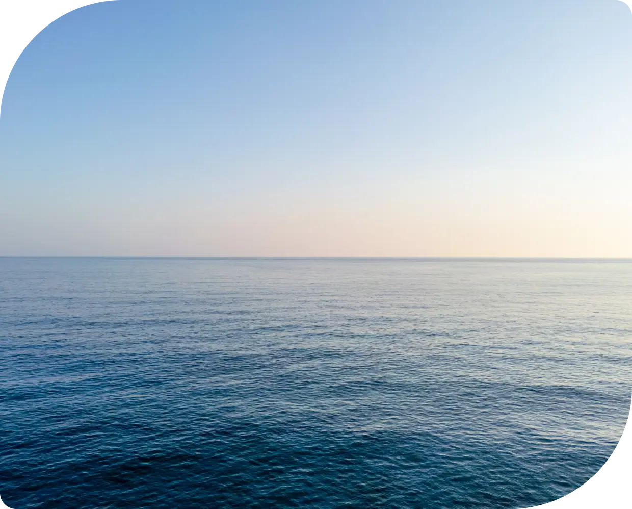 Calm ocean waters under a clear sky at sunset.